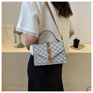 Detail of vintage patterned crossbody bag with brown leather strap and gold buckle accent