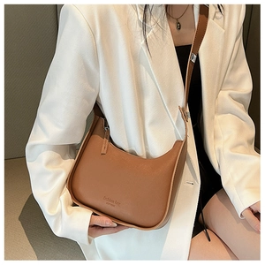 Detail view of a brown matte leather hobo bag worn with a white blazer for styling