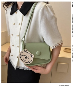 Detail of mint green crossbody bag with asymmetrical flap and cute bear pendant charm