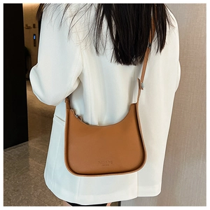 Brown half-moon saddle bag styled on a white blazer for a modern urban fashion look