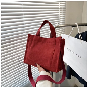 Détail d'un sac cabas en velours rouge montrant la texture et la bandoulière large