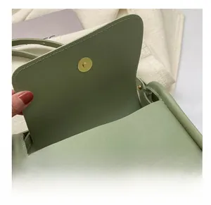 Detail view of a green leather saddle bag featuring a durable gold magnetic buckle clasp