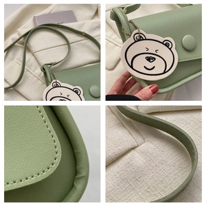 Detail showing light green faux leather crossbody bag with beige teddy bear pendant charm