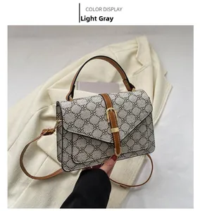 Detail shot of vintage floral crossbody bag with brown leather straps on white suit