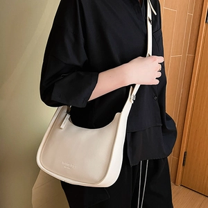 Minimalist beige shoulder bag with adjustable strap shown on a model in a modern interior