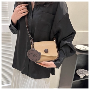 Close-up of contrast color saddle bag with flap closure and cute bear leather charm