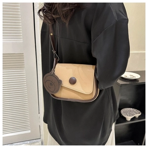 Detail of color-block saddle bag with retro round buckle and cute brown bear charm