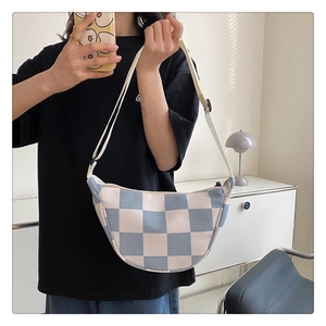 Detail of blue and white checkered knit crossbody bag with adjustable wide strap