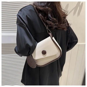 Model view of cream leather saddle bag with contrast trim and cute bear charm detail