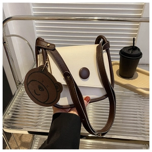 Detail of retro color-block saddle bag with magnetic closure and bear pendant