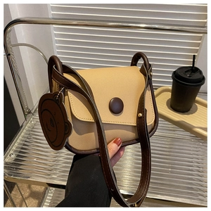 Detail of color-block saddle bag with round buckle and cute bear charm pendant
