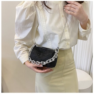 Detail einer schwarzen Strass-Umhängetasche mit silberner Kette am Outfit des Models