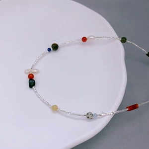 Collana di perle colorate stile bohémien con perle barocche su piatto di ceramica