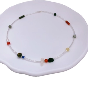 Collana di perle barocche e pietre preziose colorate su un piatto di ceramica bianca