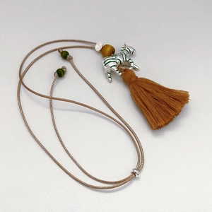 Zebra necklace with long yellow tassel and green bead accents on woven cord lanyard