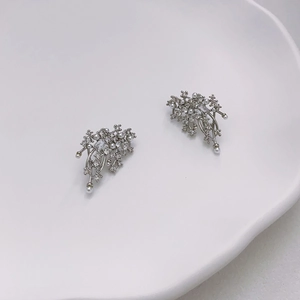 Sparkling leaf stud earrings with pavé zircons and pearls on white ceramic plate