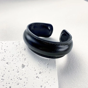 Close-up of wide black genuine leather cuff bracelet with fine stitching on stone