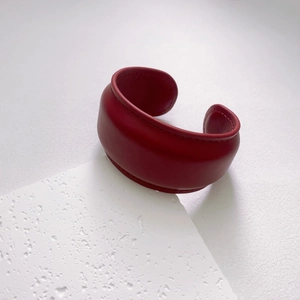 Detail view of deep red wide leather bracelet with fine stitching and natural texture