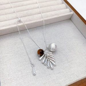 Collier à perles argentées avec pierre œil de tigre et franges métalliques sur présentoir