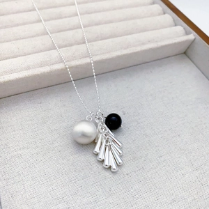 Collier argenté élégant avec perle blanche, bille noire et pendentif à pompon métal