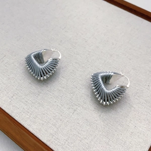 Macro detail of blue hand-wrapped cotton thread on triangular earrings with silver clasp