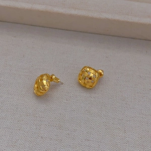 Macro shot of gold square stud earrings featuring intricate woven texture and matte finish