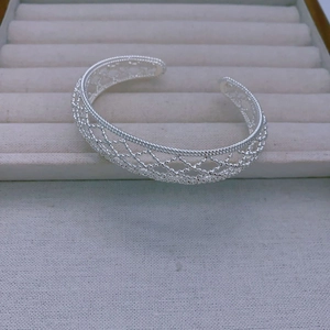 Detailed view of silver open cuff bracelet featuring an intricate hollow lattice mesh pattern