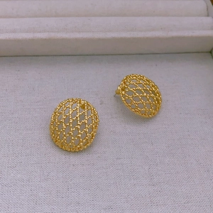 Detailed view of gold-plated mesh hollow oval stud earrings on white textured fabric