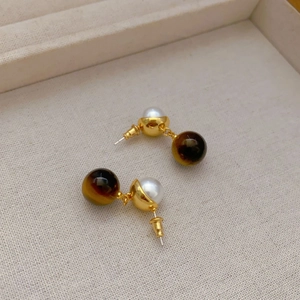 French style gold plated earrings featuring tiger eye stones and white pearls on beige fabric