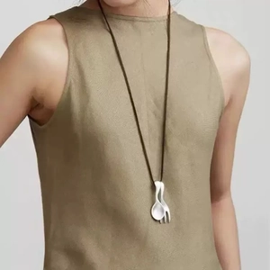 Artistic silver spoon and fork pendant necklace on minimalist olive green sweater