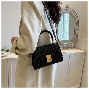 Close-up of black crocodile textured handbag with golden twist lock and woven handle