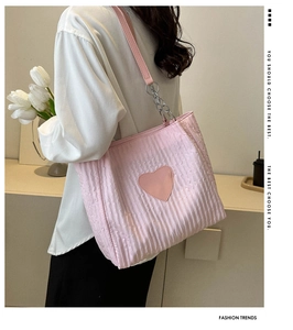 Dettaglio della borsa tote rosa a pieghe con toppa a cuore e tracolla a catena