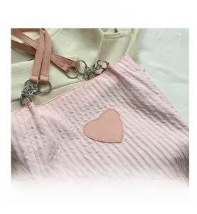 Dettaglio della borsa tote rosa a pieghe con patch a cuore in pelle e catena metallica
