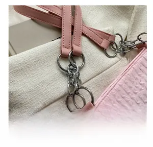 Dettaglio della trama arricciata rosa e catena in metallo argento di una borsa donna