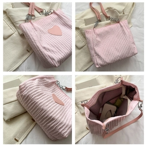 Viste dettagliate di una borsa tote rosa trapuntata con patch cuore e tracolla a catena