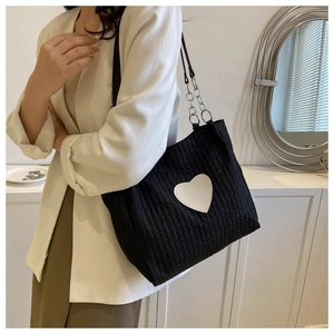 Dettaglio della borsa tote nera intrecciata con cuore bianco e tracolla a catena