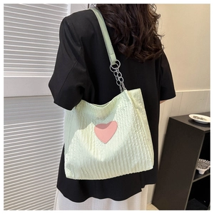 Dettaglio della borsa tote verde menta con patch a cuore rosa e tracolla a catena