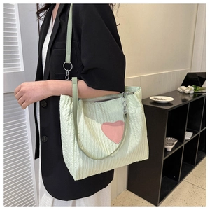 Dettaglio della borsa tote verde chiaro con trama a pieghe e un cuore rosa applicato