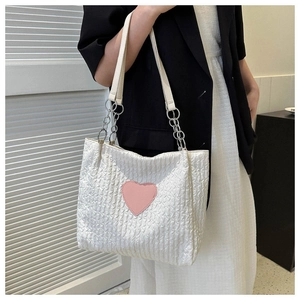 Dettaglio della borsa tote in tela bianca con cuore rosa e tracolla a catena