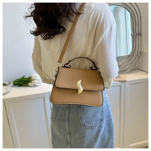 Close-up of khaki trapezoid bag featuring a gold S-shaped buckle and leather texture