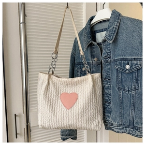 Dettaglio della borsa tote in tela crema con patch cuore rosa e trama a pieghe