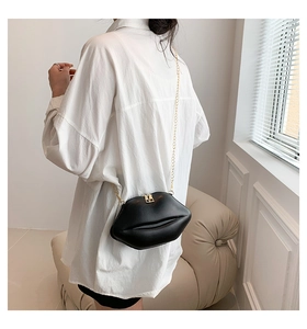 Détail du sac bandoulière noir en forme de lèvres avec chaîne dorée sur mannequin