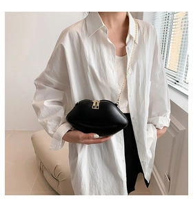 Détail d'un sac à main chic en forme de lèvres noires avec chaîne dorée et fermeture