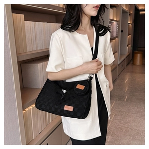 Detail of black checkerboard canvas crossbody bag with a round coin purse on a shoulder strap