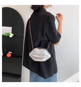 Détail du mini sac à main argenté en forme de lèvres avec bandoulière dorée