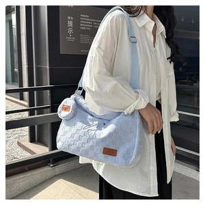 Detail of light blue quilted tote bag with wide strap and detachable round coin purse