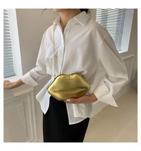 Sac à main en forme de lèvres dorées porté en bandoulière avec finition brillante