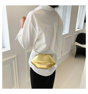 Détail d'un sac à main doré en forme de lèvres avec fine bandoulière chaîne