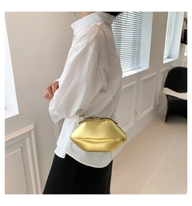 Détail d'un sac chic doré en forme de lèvres avec une chaîne en métal et un fini mat