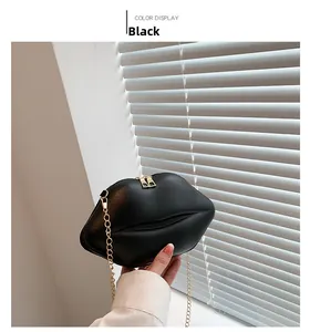 Détail du sac à bandoulière noir en forme de lèvres avec chaîne dorée et double zip